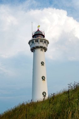 Yaklaşma. 28 metre yüksekliğindeki deniz feneri J.C.J. Egmond 'daki van Speijk aan Zee, Kuzey Hollanda, Hollanda' da, kumsaldaki kum tepelerinde ve bulutlarda