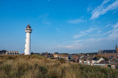 Yaklaşma. 28 metre yüksekliğindeki deniz feneri J.C.J. Egmond 'daki van Speijk aan Zee, Kuzey Hollanda, Hollanda' daki bazı otlu evlerle