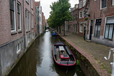 Bir su kanalında evler, küçük bir sokak ve Hollanda 'nın eski Alkmaar kasabasında tekneleri olan.