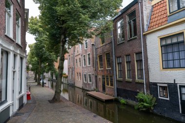Bir su kanalında evler, küçük bir sokak ve Hollanda 'nın eski Alkmaar kasabasında tekneleri olan.