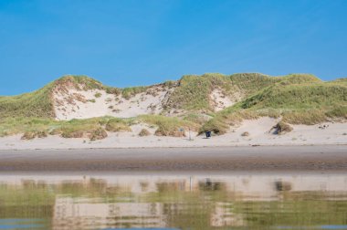 Kum tepecikleri durgun sulara yansıyor.