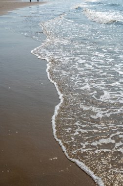 Deniz kıyısındaki kumlu sahilde dalgalar