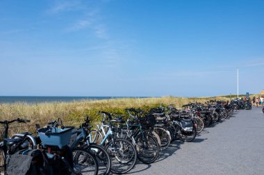 Egmond aan Zee, Hollanda, 1 Eylül 2024 - Hollanda 'nın Egmond aan Zee kasabasındaki kumlu plajda mavi gökyüzü ile park edilmiş birçok bisiklet
