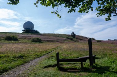 Radar kubbesi, Almanya 'nın yüksek Rhoen bölgesinde Wasserkuppe' nin zirvesinde, büyük bir ağaç dalı ve önde bir bank ile, güzel bir yaz günü mavi gökyüzü ile