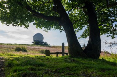 Radar kubbesi, Almanya 'nın yüksek Rhoen bölgesindeki Wasserkuppe' nin zirvesinde, ön planda büyük bir ağaç ve bir bank ile, güzel bir yaz günü mavi gökyüzü ile