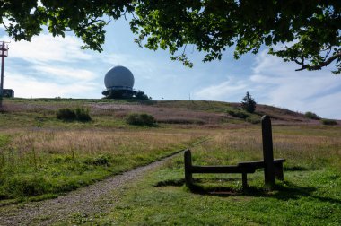 Radar kubbesi, Almanya 'nın yüksek Rhoen bölgesinde Wasserkuppe' nin zirvesinde, büyük bir ağaç dalı ve önde bir bank ile, güzel bir yaz günü mavi gökyüzü ile