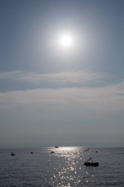 Denizde mavi gökyüzü olan bazı tekneler ve sudaki güneşin yansımaları