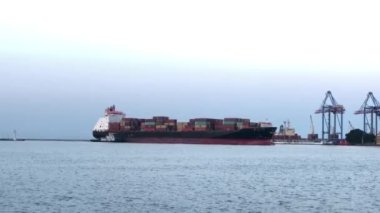 Deniz limanında konteynırları olan bir gemi. Konteynırlarla dolu bir gemi boşaltılıyor. Limanda konteyner gemisi var..