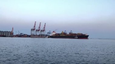 Deniz limanında konteynırları olan bir gemi. Konteynırlarla dolu bir gemi boşaltılıyor. Limanda konteyner gemisi var..