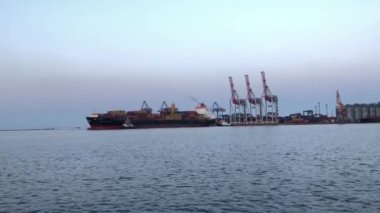 Deniz limanında konteynırları olan bir gemi. Konteynırlarla dolu bir gemi boşaltılıyor. Limanda konteyner gemisi var..