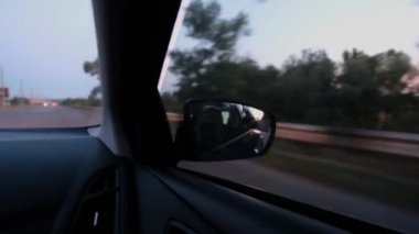 Bir arabanın dikiz aynasında gün batımının yansıması. Arabayla seyahat et. Araba dikiz aynaları.