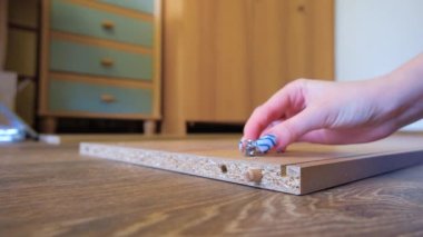 Kız talimatlara göre dolap mobilyalarını topluyor. Mobilyalar evde toplanıyor. Mobilya montajı yakın plan.