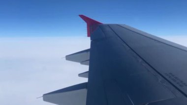 Pencereden geçen uçak kanadı. Uçakla bulutların üzerinde uçmak. Kanat ve bulutlardaki lombozdan bak.