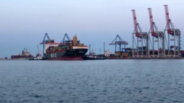 Deniz limanında konteynırları olan bir gemi. Konteynırlarla dolu bir gemi boşaltılıyor. Limanda konteyner gemisi var..
