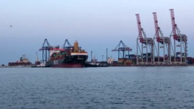 Deniz limanında konteynırları olan bir gemi. Konteynırlarla dolu bir gemi boşaltılıyor. Limanda konteyner gemisi var..