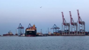 Deniz limanında konteynırları olan bir gemi. Konteynırlarla dolu bir gemi boşaltılıyor. Limanda konteyner gemisi var..