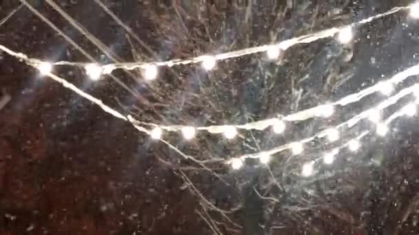 雪落在一个花环的后面 街上装饰灯的后面下着雪 — 图库视频影像
