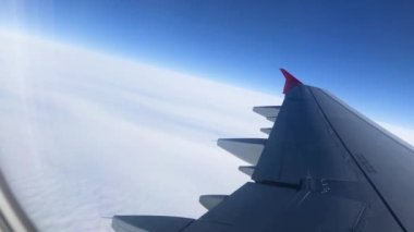 Pencereden geçen uçak kanadı. Uçakla bulutların üzerinde uçmak. Kanat ve bulutlardaki lombozdan bak.