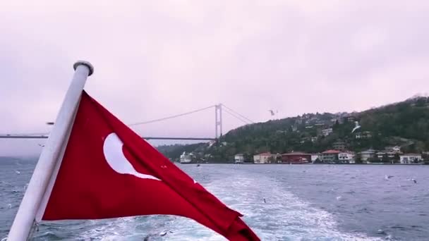 ボスポラス川を背景にしたトルコ国旗 ボスポラスを背景にトルコ国旗がなびく 美しい夕日を背景にトルコの国旗 — ストック動画