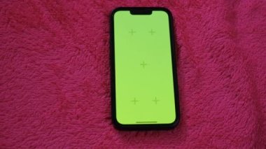 Telefon ekranındaki krom anahtar. Krom anahtarlı telefon. Pembe arkaplanda yeşil ekranlı telefon.