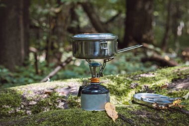 Portatif bir sobada çay ve yiyecek için kaynar su ve vahşi doğanın ortasında paslanmaz çelik bir tencerede. Yürüyüş yaşam tarzı.