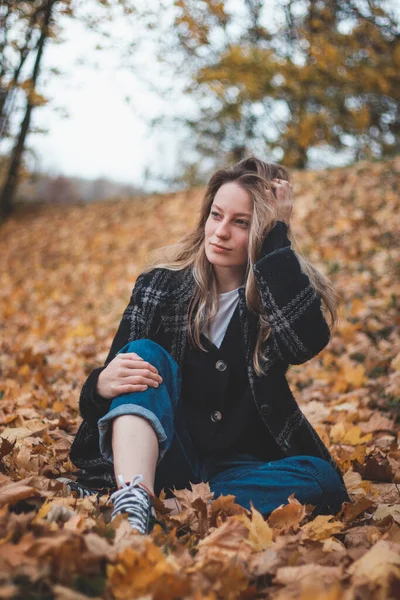 Uśmiechnięta Brunetka Siedząca Stercie Kolorowych Liści Dębowym Lesie Dotyka Jej — Zdjęcie stockowe