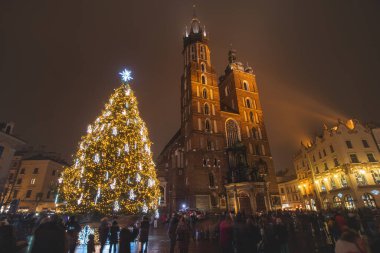 3.12. 2022 - Krakow. Polonya 'nın başkenti Krakow' dan Rynek Parıltısı adlı ana meydanda nefes kesici bir katedral ve Noel ağacı var..