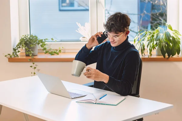 goal-oriented brown-haired businessman is on the phone with his supervisor and chatting. Making and arranging an appointment with a client. A young visionary in his office.