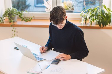 Brown-haired entrepreneur rests his stock market returns on a calculator and calculates the fair value of a given company he intends to buy in the next few moments. Working with the stock market.