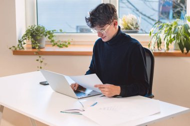 Brown-haired entrepreneur rests his stock market returns on a calculator and calculates the fair value of a given company he intends to buy in the next few moments. Working with the stock market.