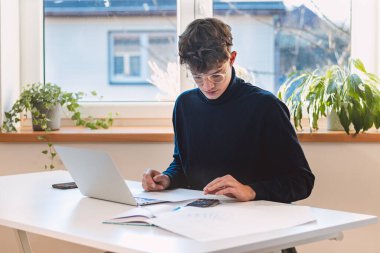 Brown-haired entrepreneur rests his stock market returns on a calculator and calculates the fair value of a given company he intends to buy in the next few moments. Working with the stock market.
