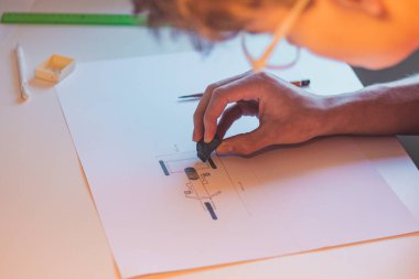 Brown-haired young architect creates new product designs for a new futuristic world. Working with your own creativity. Compass, pencil, ruler and paper. Creative home office.