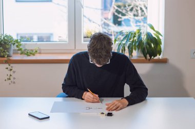 Brown-haired young architect creates new product designs for a new futuristic world. Working with your own creativity. Compass, pencil, ruler and paper. Creative home office.