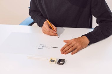 Brown-haired young architect creates new product designs for a new futuristic world. Working with your own creativity. Compass, pencil, ruler and paper. Creative home office.