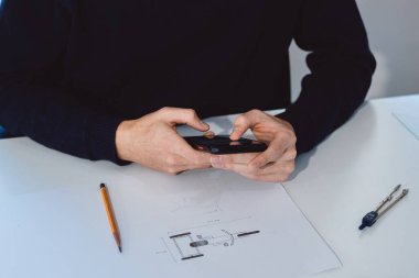 Close-up of a bright, businesslike, aspiring and young architect at his desk in his office. Drawing a new product on white paper. Work of a product designer. Searching for an idea, finding inspiration.