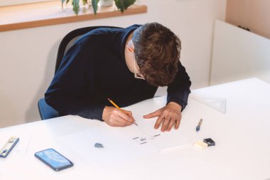 Brown-haired young architect creates new product designs for a new futuristic world. Working with your own creativity. Compass, pencil, ruler and paper. Creative home office.