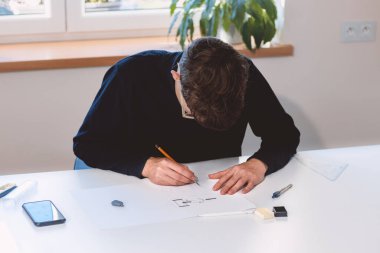 Brown-haired architect creates new product designs for a new futuristic world. Working with your own creativity. Compass, pencil, ruler and paper. Creative home office.