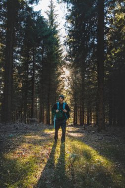 Walk through a fragrant and pine forest at sunset in the remote corners of the Beskydy mountains, Czech republic. Man with a backpack on his back in autumn temperatures.