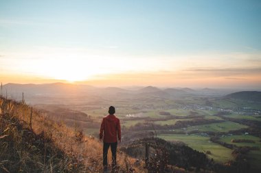 Amazing moment at sunrise as a hiker celebrates his climb up the mountain and completing another point on the map. Trying to complete the journey. Ondrejnik, Beskydy mountains, Czech Republic.