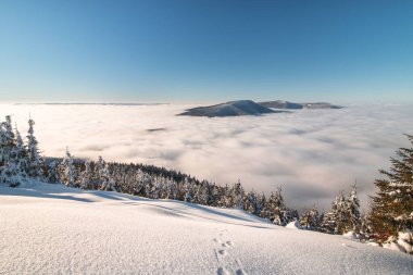 Çek Cumhuriyeti 'ndeki Beskydy bölgesinin dağları şehirlerden yükselen kalın beyaz bir tepkiye doğru batıyor. Orta Avrupa 'da kış masalı manzarası.