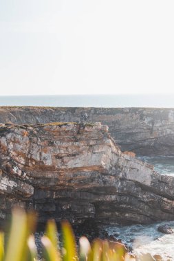 Yürüyüşçü başarısını kutluyor. Portekiz, Odemira 'daki Vila Nova de Milfontes' te öğleden sonra güneşinde çakıl taşı plajlı nefes kesici uçurumlar. Rota Vicentina 'nın izinden..