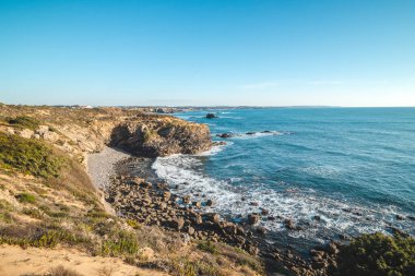Portekiz, Odemira 'daki Vila Nova de Milfontes' te öğleden sonra güneşinde çakıl taşı plajlı nefes kesici uçurumlar. Rota Vicentina 'nın izinden. Balıkçı patikası.