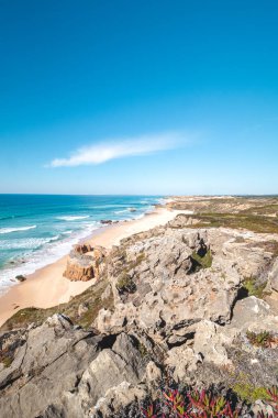 Portekiz 'in Odemira kenti Vila Nova de Milfontes yakınlarındaki Atlantik kıyısında Praia do Malhao Sul' un kumlu plajını kayalar çevrelemektedir. Rota Vicentina 'nın izinden. Balıkçı patikası.