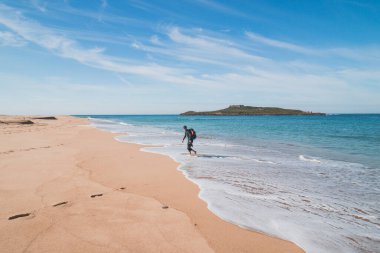 Porto Covo, Portekiz yakınlarındaki kumlu bir plajda Atlantik Okyanusu 'nun dalgalarından kaçan genç, tutkulu siyah saçlı dobby. Rota Vicentina 'nın izinden..
