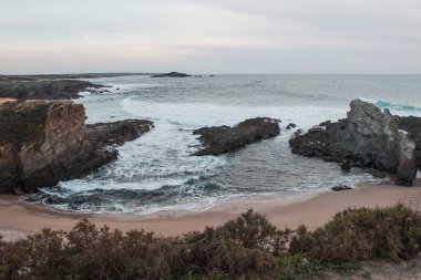 Praia dos Buizinhos 'un kumlu plajının güzelliği Porto Covo' da kayalıklarla gün batımında Portekiz 'in batısında, Rota Vicentina yürüyüşünün başlangıcında.