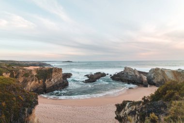 Beauty of the sandy beach of Praia dos Buizinhos with the cliffs at Porto Covo at sunset in western Portugal, at the start of the Rota Vicentina trek. clipart