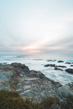 Fırtınalı Atlantik Okyanusu gücünü Porto Covo, Portekiz açıklarında gün batımında kayalara çarpan dalgalarla gösteriyor. Balıkçı Yolu 'nun güzelliği, Rota Vicentina.