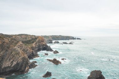 Portekiz 'in batısındaki Zambujeira Do Mar kasabası yakınlarındaki Atlantik Okyanusu kıyısındaki engebeli kaya ve uçurum Algarve' nin ünlü turistik bölgesinde. Gün ışığı.