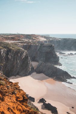 Atlantik kıyısındaki tipik manzara. Portekiz 'in batısındaki Odemira bölgesinde kumlu plajları olan yüksek kayalık kayalıklar. Balıkçı Patikası boyunca gezinen, Rota Vicentina.