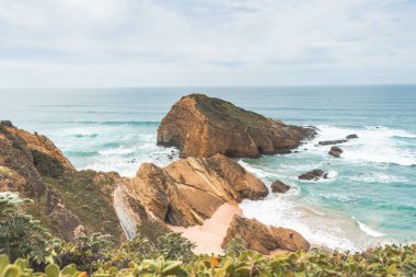 Portekiz 'in Odemira bölgesindeki Atlantik Okyanusu' nun dalgalarıyla sulanan sarı-turuncu kumlara sarp kayalıklar düşüyor. Balıkçı Yolu 'nun ayak izlerinde, Rota Vicentina..